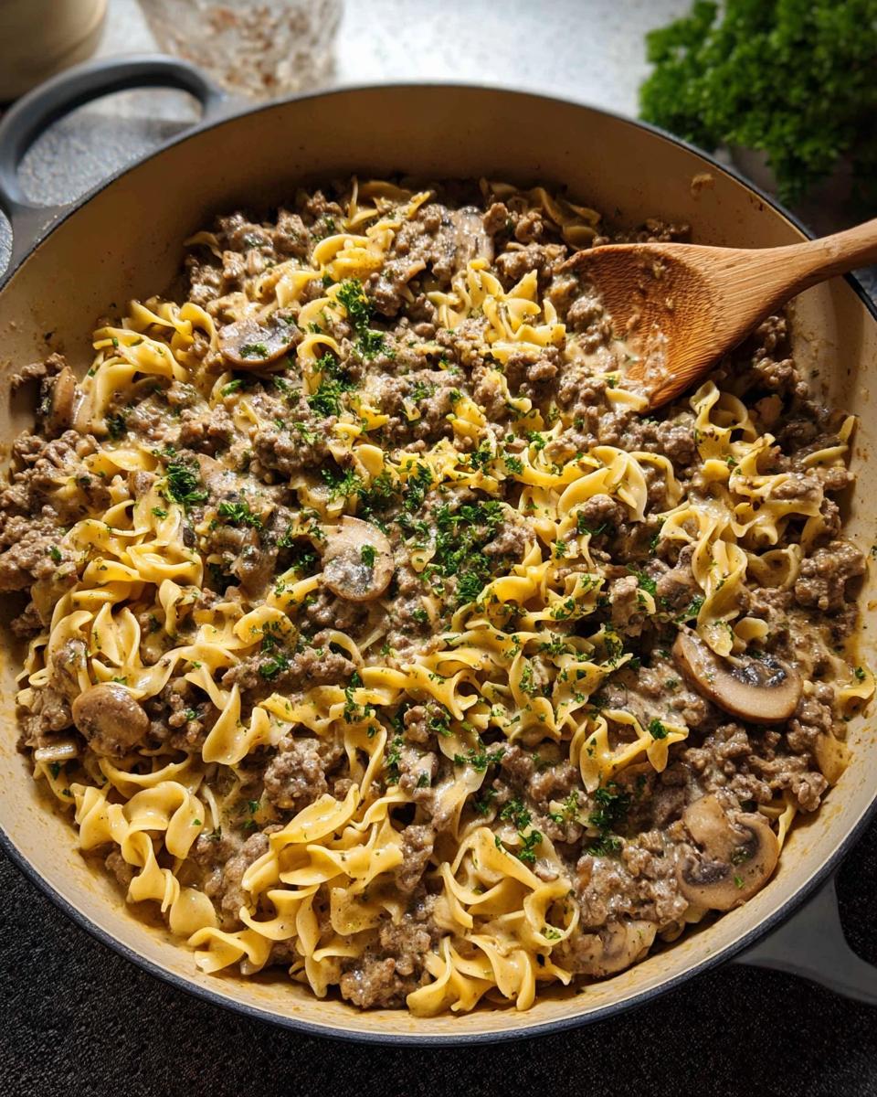 Close-up of a creamy ground beef and mushroom skillet pasta dish, garnished with parsley.