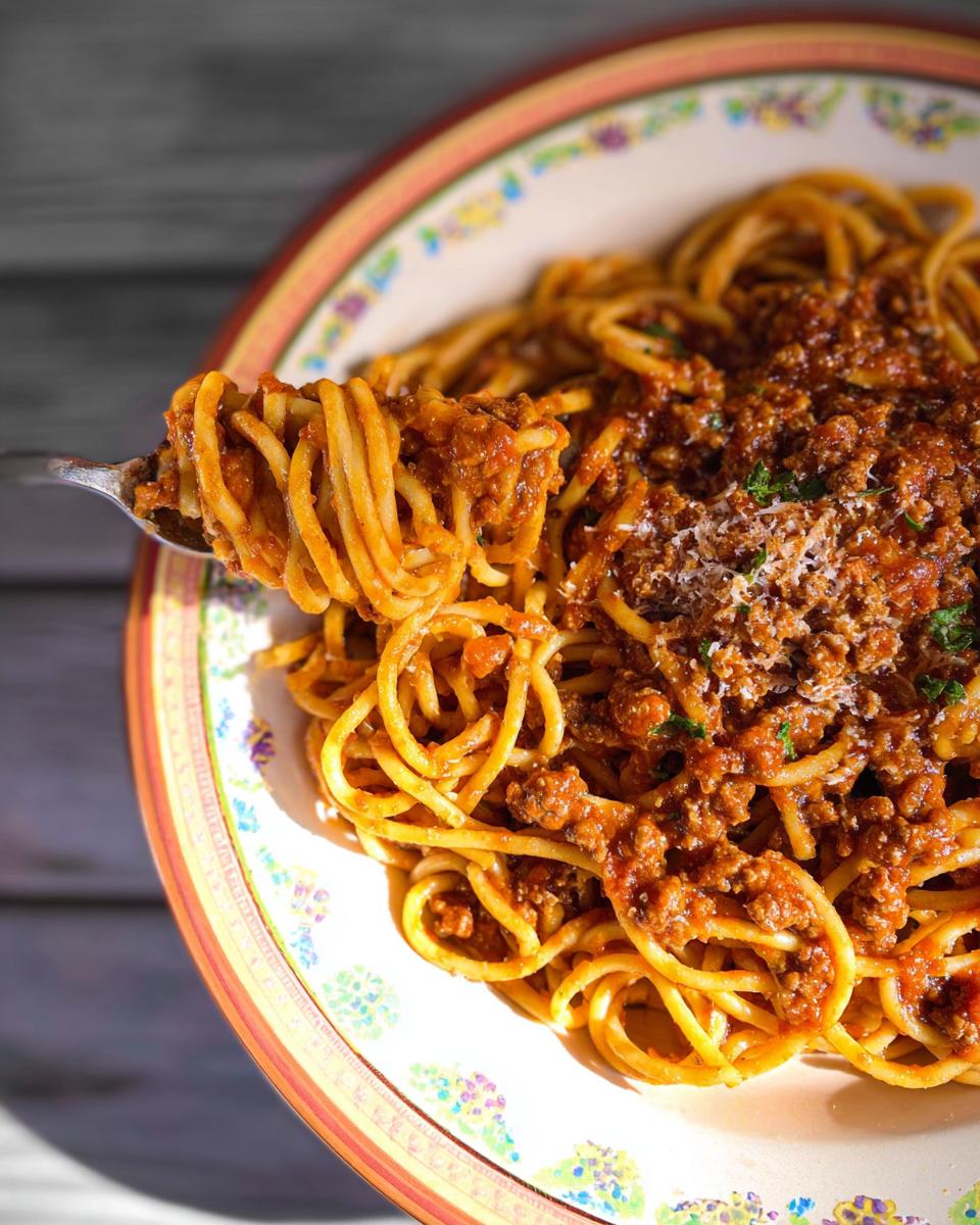 A fork lifting a generous portion of spaghetti with rich ground beef bolognese sauce, a perfect example of best ground beef recipes for busy nights.