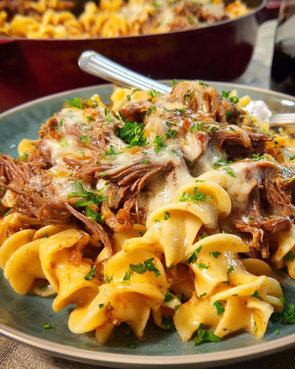 A close-up of a bowl of pasta topped with shredded beef and melted cheese, garnished with parsley. A classic dinner recipe with a twist.